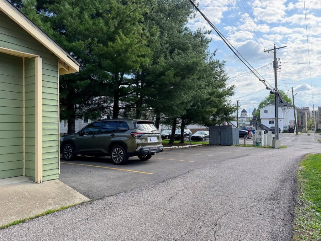 Parking area beside Mother Nurtured Midwifery office in Bloomington, Indiana with trees and nearby buildings